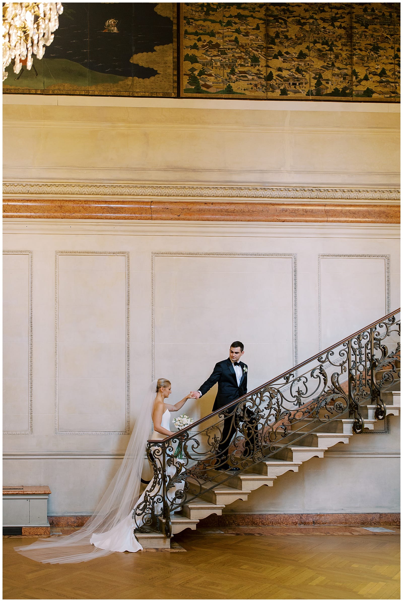 man in black tux escorting a woman in a wedding gown up the marble staircase at the Anderson House