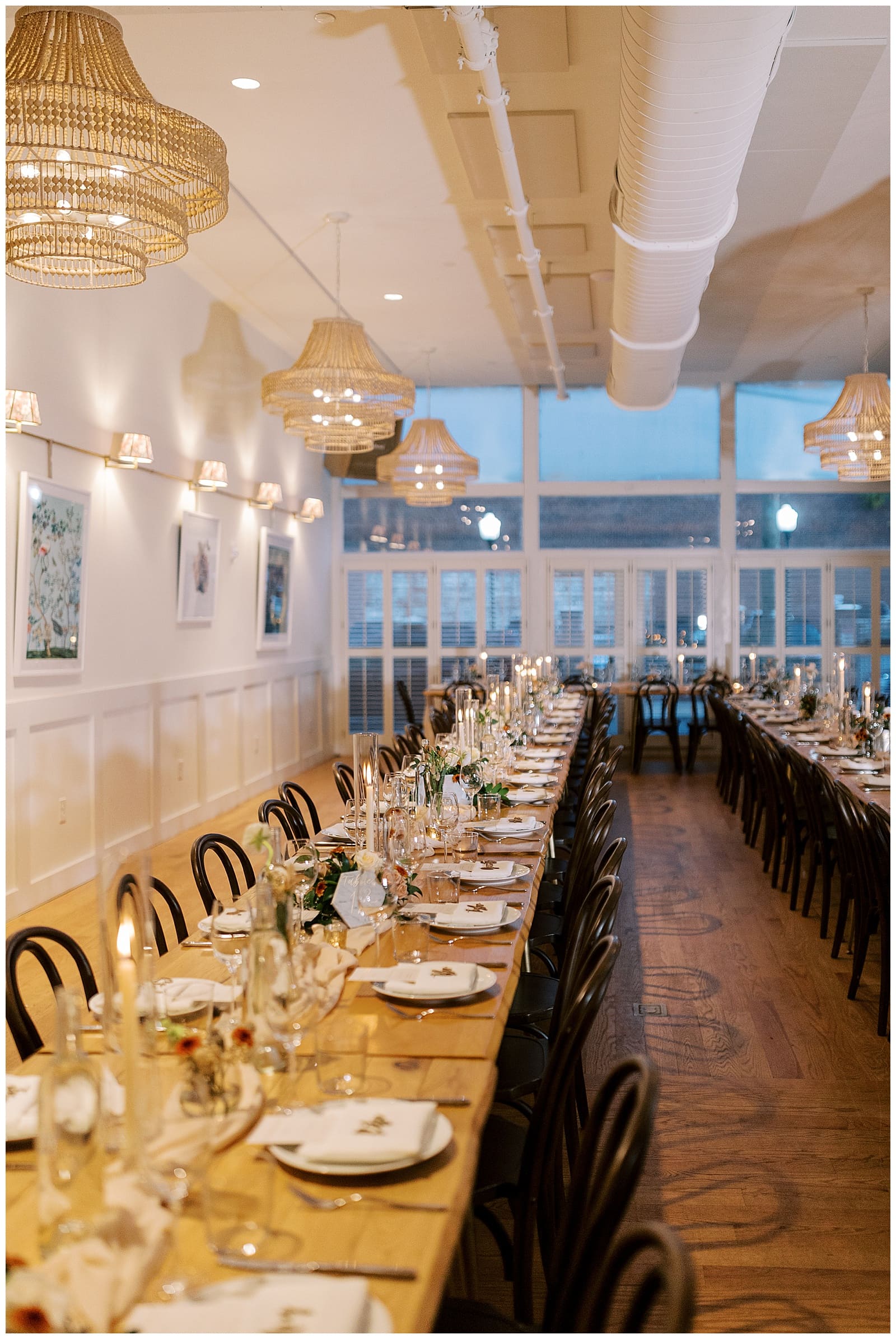 Image of the reception space at the Common House Richmond decorated with long tables, lots of chairs, and candles lit. 